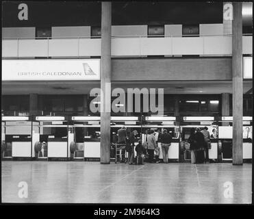 Passagiere, die ihr Gepäck an den britischen Caledonian-Schaltern am London Gatwick Airport, England, aufgeben. Stockfoto