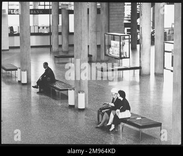 Passagiere, die auf den eher unbequem aussehenden modernen Sitzen am London Gatwick Airport, England sitzen. Stockfoto