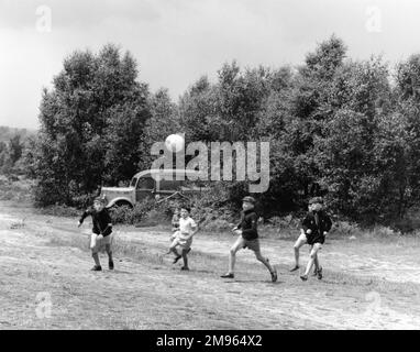 Eine Gruppe Pfadfinder haben einen Kick auf einem staubigen Fleck Ödland. Pfadfinder spielen Ball Stockfoto