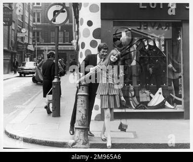 Ein passend gekleidetes Paar, das in der Carnaby Street einkauft, dem angesagten Zentrum des schwingenden Londons. Stockfoto