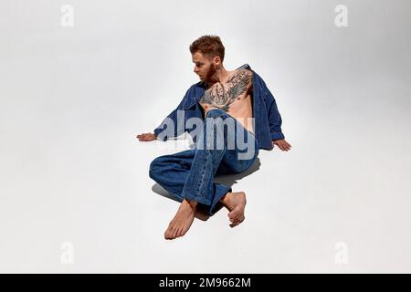 Porträt eines jungen 30-jährigen tanzenden Mannes. Perfekte Muskelform. Tattoo-Körperkunst. Konzept von Mode, Stil, Körperästhetik, Schönheit, Männermode Stockfoto