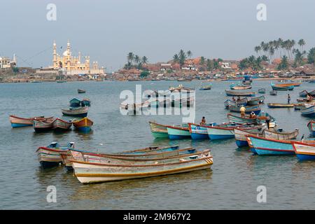 Fischerboote in der Bucht, mit einer Moschee im Hintergrund, in Vishinjam, Trivandrum, Kerala State, Indien. Stockfoto