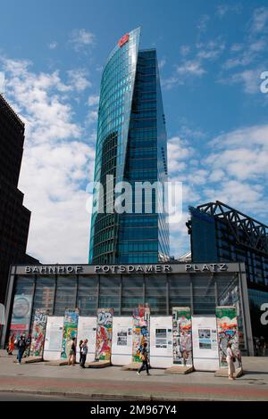 Ein moderner Wolkenkratzer auf dem Potsdamer Platz, Berlin, ragt über einer Ausstellung einiger Überreste der Berliner Mauer. Stockfoto