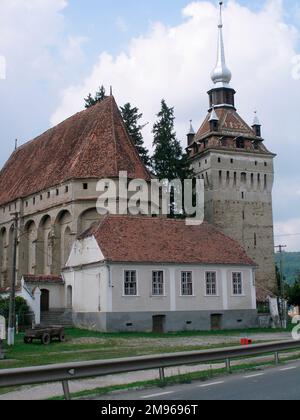 Blick auf eine alte befestigte Kirche in der mittelalterlichen Stadt Sighisoara in Siebenbürgen, Rumänien. Auf der rechten Seite befindet sich das Wahrzeichen der Stadt, ein 1360 erbauter Uhrenturm. Stockfoto