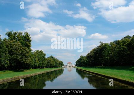 Blick auf den Nymphenburg-Park in München, Bayern, Deutschland, mit dem Palast in der Ferne am Ende eines langen Wasserabschnitts. Stockfoto