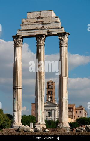 Blick auf drei korinthische Säulen im Forum Romanum, oder Forum Romanum, mit der Basilika di Massenzio (Basilika von Maxentius und Konstantin) im Hintergrund. Stockfoto