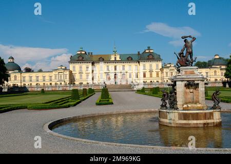 Blick auf Schloss Drottningholm und einen Teil des Parks im Stockholmer Bezirk, Uppland, Schweden, mit einem Brunnen im Vordergrund. Der Palast wurde Ende des 16. Jahrhunderts erbaut und ist die private Residenz der schwedischen Königsfamilie. Stockfoto