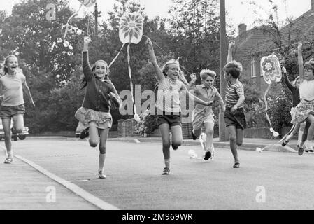 Eine Gruppe von Kindern in Horley, Surrey, die mit ihren Drachen eine Straße entlang laufen und eine wunderbare Zeit haben. Stockfoto