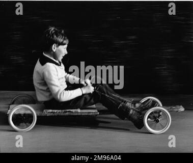 Ein Junge fährt mit einem selbstgemachten Go-Kart in Horley, Surrey. Stockfoto