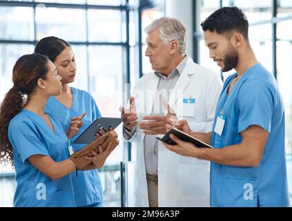 Die Anwesenheit des Arztes ist der Beginn der Heilung. Eine Gruppe von Ärzten, die sich in einem Krankenhaus unterhalten. Stockfoto