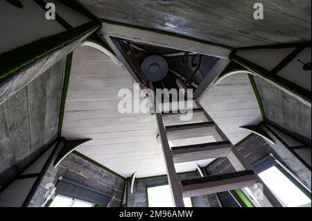 Weiße senkrechte Holztreppe zum zweiten Stock vom Wohnzimmer des Sommerhauses. Pyramidenförmiger Bungalow von innen. Fußbodenwände Decken Treppen verrückt Stockfoto