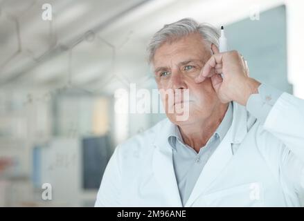 Das ist eine Angelegenheit, die ich lösen muss. Ein leitender Wissenschaftler, der Gleichungen auf einem Glasbildschirm in einem Labor löst. Stockfoto