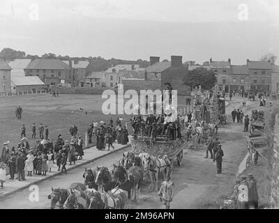 Straßenszene, die einen Teil der Sanger's Circus Parade während eines Besuchs in Haverfordwest, Pembrokeshire, Dyfed, Südwales zeigt. Die erste dieser beiden aufwändigen Pferdekutschen umfasst einen Löwen und ein Lamm, wobei Reiter in schicken Kostümen gekleidet sind. Die Leute auf dem Bürgersteig halten an und schauen nach. Sanger war ein berühmter Zirkusimpresario, der seit den 1850er Jahren spektakuläre Shows an großen Veranstaltungsorten im ganzen Land veranstaltete. Stockfoto