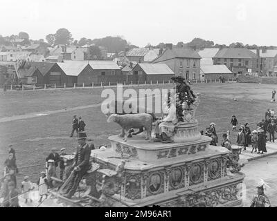 Straßenszene, die einen Teil der Sanger's Circus Parade während eines Besuchs in Haverfordwest, Pembrokeshire, Dyfed, Südwales zeigt. In dieser aufwendigen Pferdekutsche befinden sich ein Löwe und ein Lamm, wobei Reiter in schicken Kostümen gekleidet sind. Die Leute auf dem Bürgersteig halten an und schauen nach. Sanger war ein berühmter Zirkusimpresario, der seit den 1850er Jahren spektakuläre Shows an großen Veranstaltungsorten im ganzen Land veranstaltete. Stockfoto