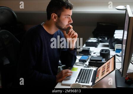 Junger Mann, der einen Computer in Montrouge, Frankreich, benutzt Stockfoto