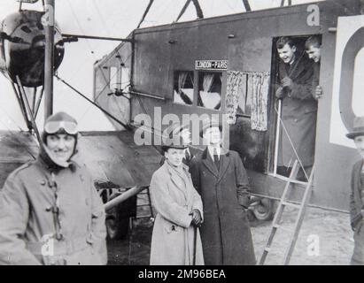 Eine Gruppe von Passagieren mit einem Flugzeug, das sie auf einem Flug von London nach Paris in den frühen Tagen der Luftfahrt mitnimmt. Der Pilot steht links, mit der Schutzbrille auf der Stirn. Das Flugzeug ist eine Handley Page O/400, die als Flugzeug für die Beförderung von Würdenträgern zwischen London und Paris für die Verhandlungen über den Vertrag von Versailles umgebaut wurde. Stockfoto