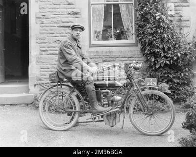 Ein Mann auf einem frühen Motorrad, vielleicht ein Triumph, zugelassen Eine 2421, vor einem Haus. Stockfoto