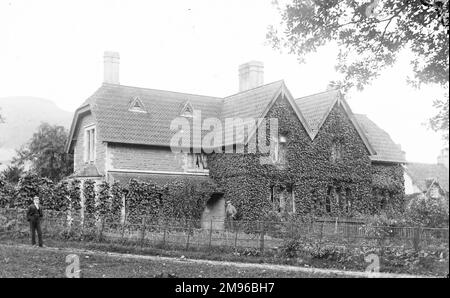 Ein großes Haus und Garten in Crickhowell, Powys, Mid Wales. Das Haus ist aus Stein gebaut, ist ziemlich überwuchert mit Efeu und hat gemusterte Fliesen auf dem Dach. Stockfoto