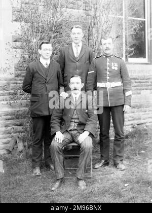 Ein Familienfoto in einem Garten, mit einem Vater und seinen drei Söhnen, einer davon in Uniform, während des Ersten Weltkriegs. Stockfoto