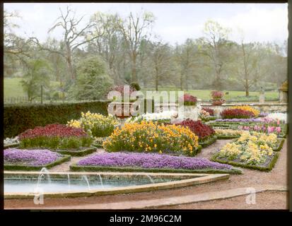 Blick auf den formellen Garten im Frühling in Abbotswood, Stow on the Wold, Gloucestershire, mit Gras und Bäumen im Hintergrund. Die Gärten wurden von Sir Edwin Lutyens geschaffen. Stockfoto