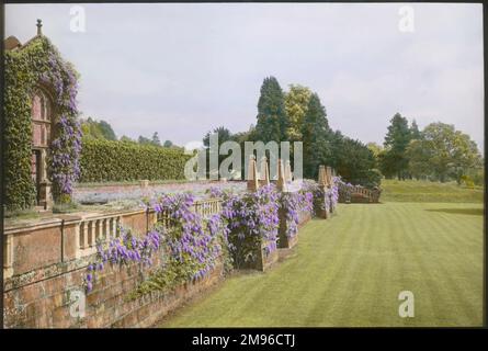 Blick auf die Terrasse im Paddockhurst, nahe Selsfield Common, West Sussex. Das Haus stammt aus dem 17. Jahrhundert und wird heute als Schule genutzt. Wisteria (eine blühende Pflanze der Familie Fabaceae) wächst entlang der Ziersteinbalustrade. Stockfoto