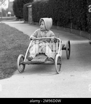 Ein kleiner Junge, der auf einem Gokart fährt, verhandelt eine Kurve im Weg. Stockfoto