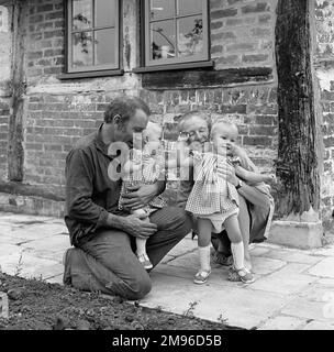 Eine vierköpfige Familie im Garten ihres Hauses - Vater, Mutter und zwei Kleinkinder. Stockfoto