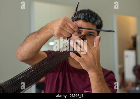 Goiania, Goiás, Brasilien – 10. Januar 2023: Detail der Hände des Friseurs, die eine Haarsträhne des Kunden trennen. Stockfoto