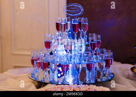 Gläser mit Rot- und Weißwein im Restaurant für einen Urlaub auf einer Spiegelfläche mit blauer Beleuchtung Stockfoto