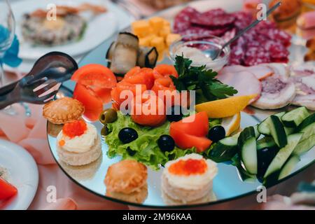 Lachsscheiben mit Zitrone, Gurke und Oliven auf einem Snackteller im Restaurant im Urlaub Stockfoto