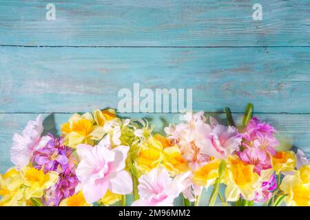 Farbenfrohe Anordnung frischer Frühlingsblumen, großer Strauß von Frühlingsblumen - Narzissen, Hyazinthen, Tulpen, Kamille auf türkisblauem Holzbalken Stockfoto