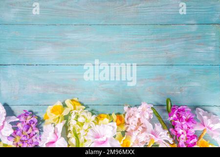 Farbenfrohe Anordnung frischer Frühlingsblumen, großer Strauß von Frühlingsblumen - Narzissen, Hyazinthen, Tulpen, Kamille auf türkisblauem Holzbalken Stockfoto