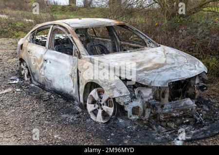 Ein ausgebranntes, modernes Auto, das in Großbritannien auf dem Müllgrund stehen gelassen wurde Stockfoto