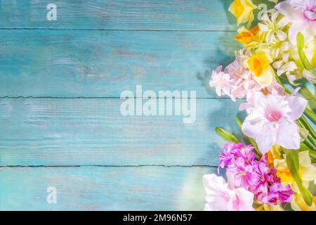 Farbenfrohe Anordnung frischer Frühlingsblumen, großer Strauß von Frühlingsblumen - Narzissen, Hyazinthen, Tulpen, Kamille auf türkisblauem Holzbalken Stockfoto