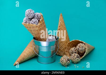 Runde Schokoladenbonbons bei Eiskrem-Cones. Waffelmais auf farbenfrohem grünen Hintergrund mit Knöpfen Stockfoto