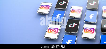 Social-Media-Konzept: Logos der Social-Media-Plattformen Facebook, Instagram und TikTok, die auf Smartphones über einem blauen Tisch angezeigt werden. Stockfoto