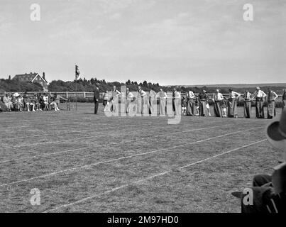 Leute auf einem Sportplatz, mit einer Reihe von Männern, die in einem Sackrennen starten. Stockfoto