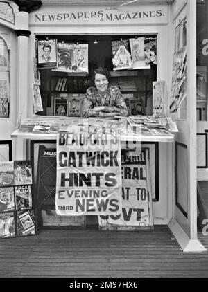 Eine Frau im Zeitungskiosk mit Zeitschriften, die überall um sie herum ausgestellt sind. Stockfoto