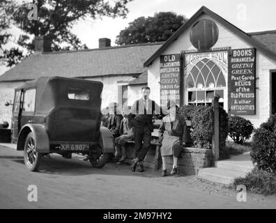 Leute, die auf einer Bank vor dem Hochzeitszimmer sitzen, auch bekannt als Old Blacksmith's Shop, Gretna Green, Dumfriesshire, Schottland. Stockfoto