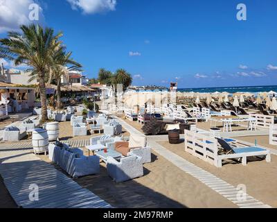 Kreta, Griechenland - 09. Oktober 2022: Strand mit Sonnenliegen und Strandrestaurant in Stalida ein bevorzugter Touristenort zum Schwimmen und Entspannen Stockfoto