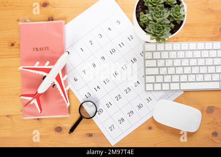 Kalender und Erinnerungen für Geschäftsreisen, Reisen und Urlaub. Gleiter auf dem Schreibtisch mit Flugzeug und Lupe, Stift und Tastatur. Markierung wichtig Stockfoto