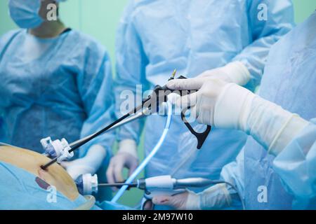 Laparoskopische Operationsinstrumente in der Hand des Chirurgen. Selektiver Fokus. Die Hand des Chirurgen in sterilen Handschuhen während der Operation. Stockfoto