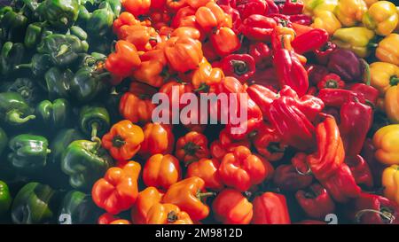 Vollformat-Nahaufnahme von roten, orangefarbenen, gelben und grünen Paprika auf einem Markt Stockfoto