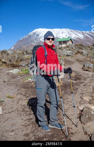 Männlicher Rucksacktourist auf der Wanderung zum Kilimandscharo-Berg. Stockfoto