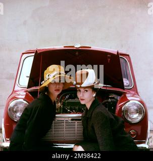 Tatler-Cover-Fotoshooting mit Fokus auf Hüte und die Motor Show -- zwei weibliche Models, die sich vor einem roten Mini-Auto posieren. Für das Cover der Tatler-Ausgabe vom 21. Oktober 1959 wurde eine Variantenaufnahme dieses speziellen Fotoshooting verwendet (siehe Abbildung 11064837). Stockfoto