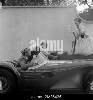 Werbung für Manns Brown Ale... männliche und weibliche Models, die sich mit einem Auto posieren, das nicht anspringt. Stockfoto