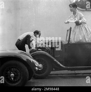 Werbung für Manns Brown Ale... männliche und weibliche Models, die sich mit einem Auto posieren, das nicht anspringt. Stockfoto