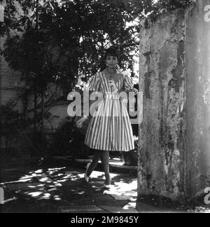 Junge Frau (Model - Geraldine Hill), die ein Kleid in einem Garten vorführt. Stockfoto