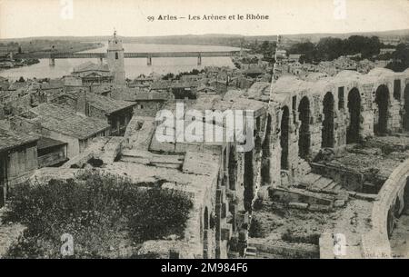 Arles France: Blick über den Rand des Ruinen römischen Amphitheaters über die Rhone. Das Amphitheater mit 120 Bögen, wie sie an den Mauern abgebildet sind, wurde ursprünglich 90AD erbaut und war Schauplatz von Wagenrennen und Hand-an-Hand-Kämpfen. In neueren Zeiten hat es Stierkämpfe, Theaterstücke und Konzerte veranstaltet. Stockfoto