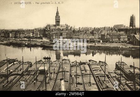 Dünkirchen, Frankreich - ein Blick über den Hafen mit gefesselten Fischerbooten im Vordergrund und das Rathaus mit einem Kirchengürtel in der Ferne. Stockfoto